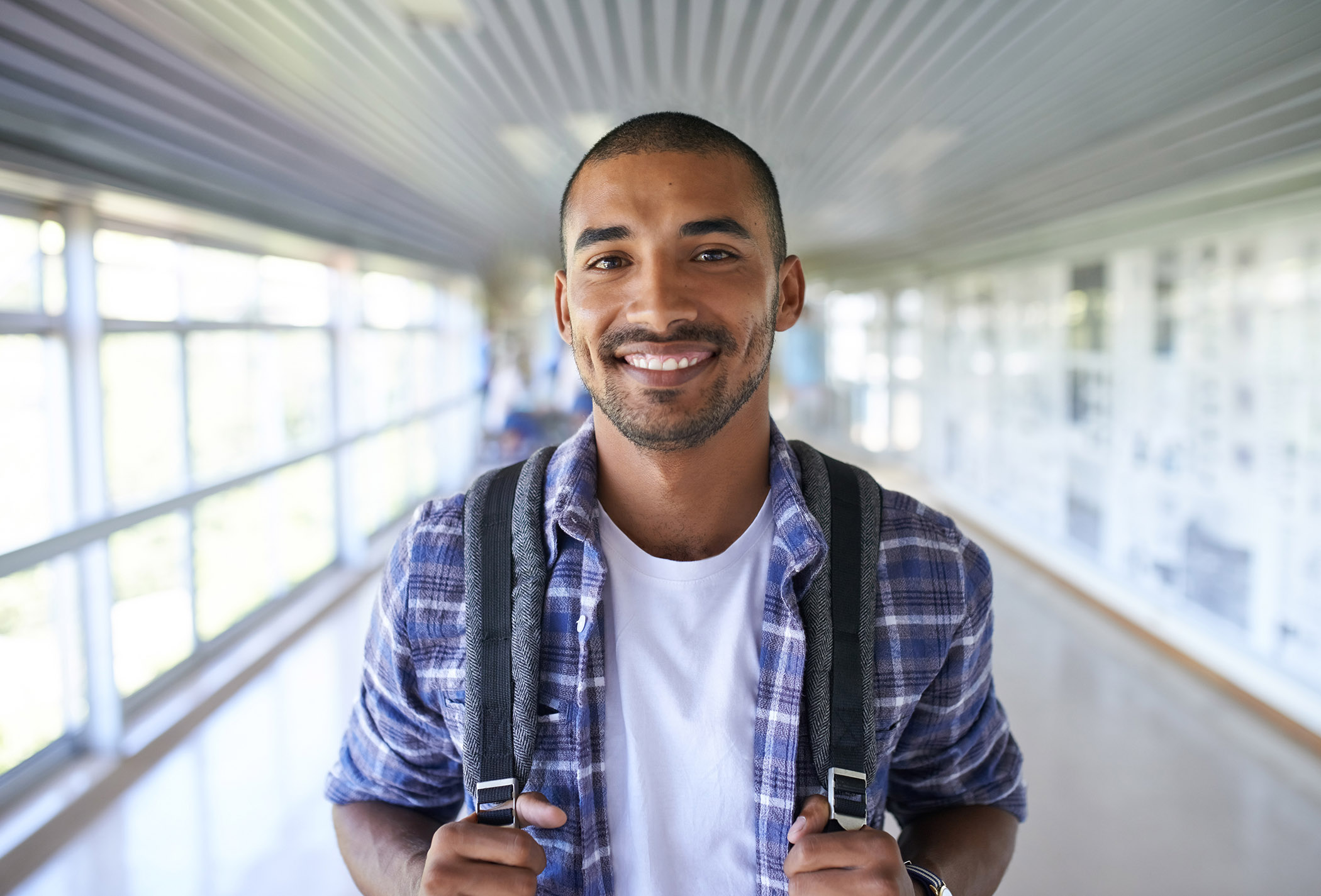 Portrait of a happy young man standing in a corridor on campus